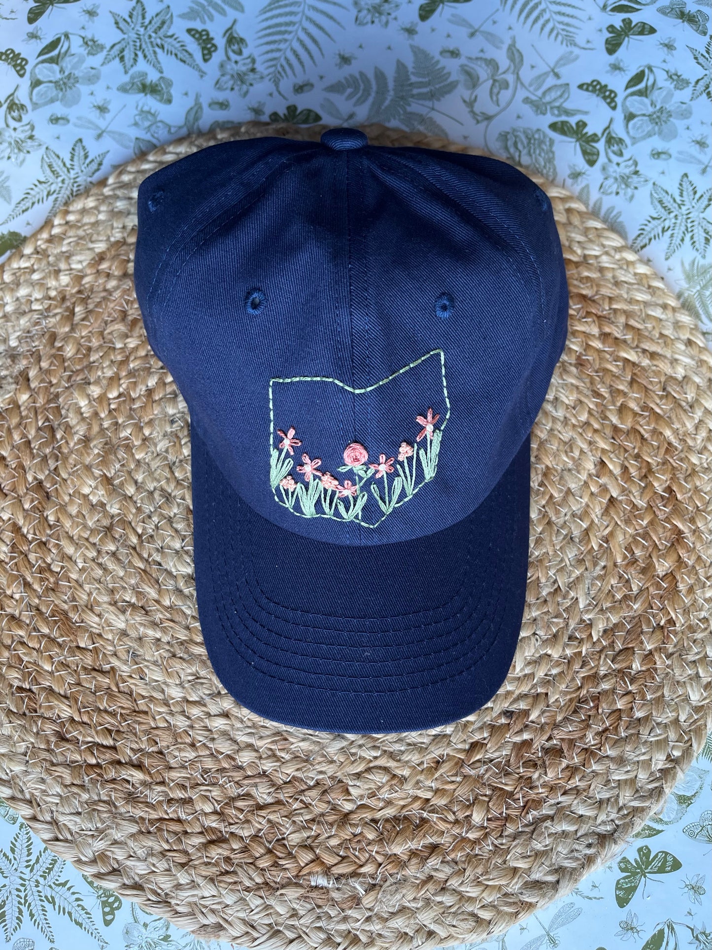 Navy blue cap with floral design on a woven surface