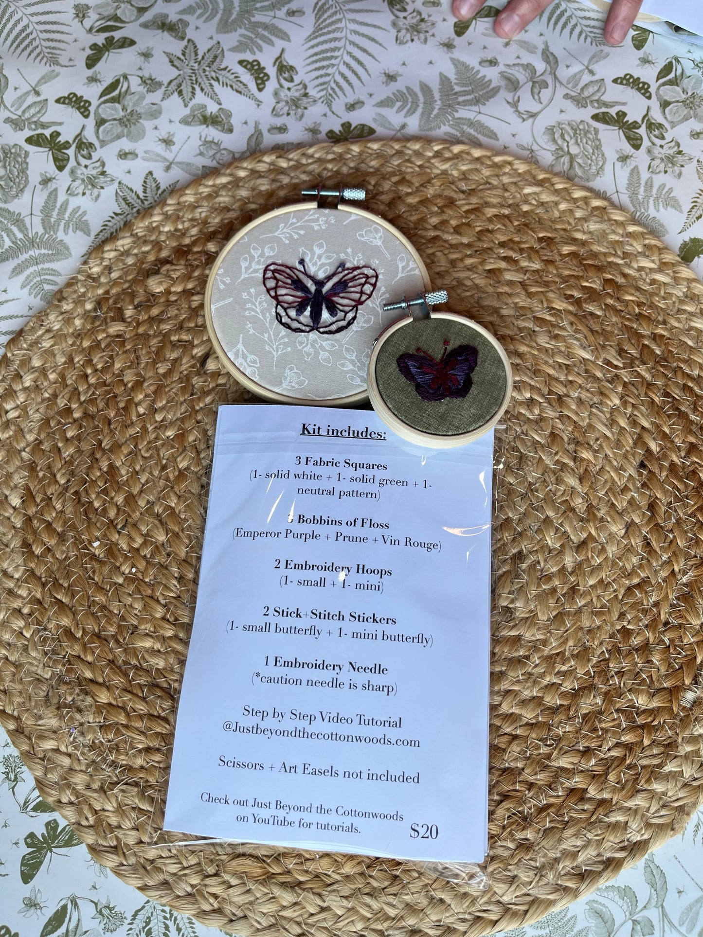 Embroidery hoop with butterfly design  and list of what is included on a textured surface