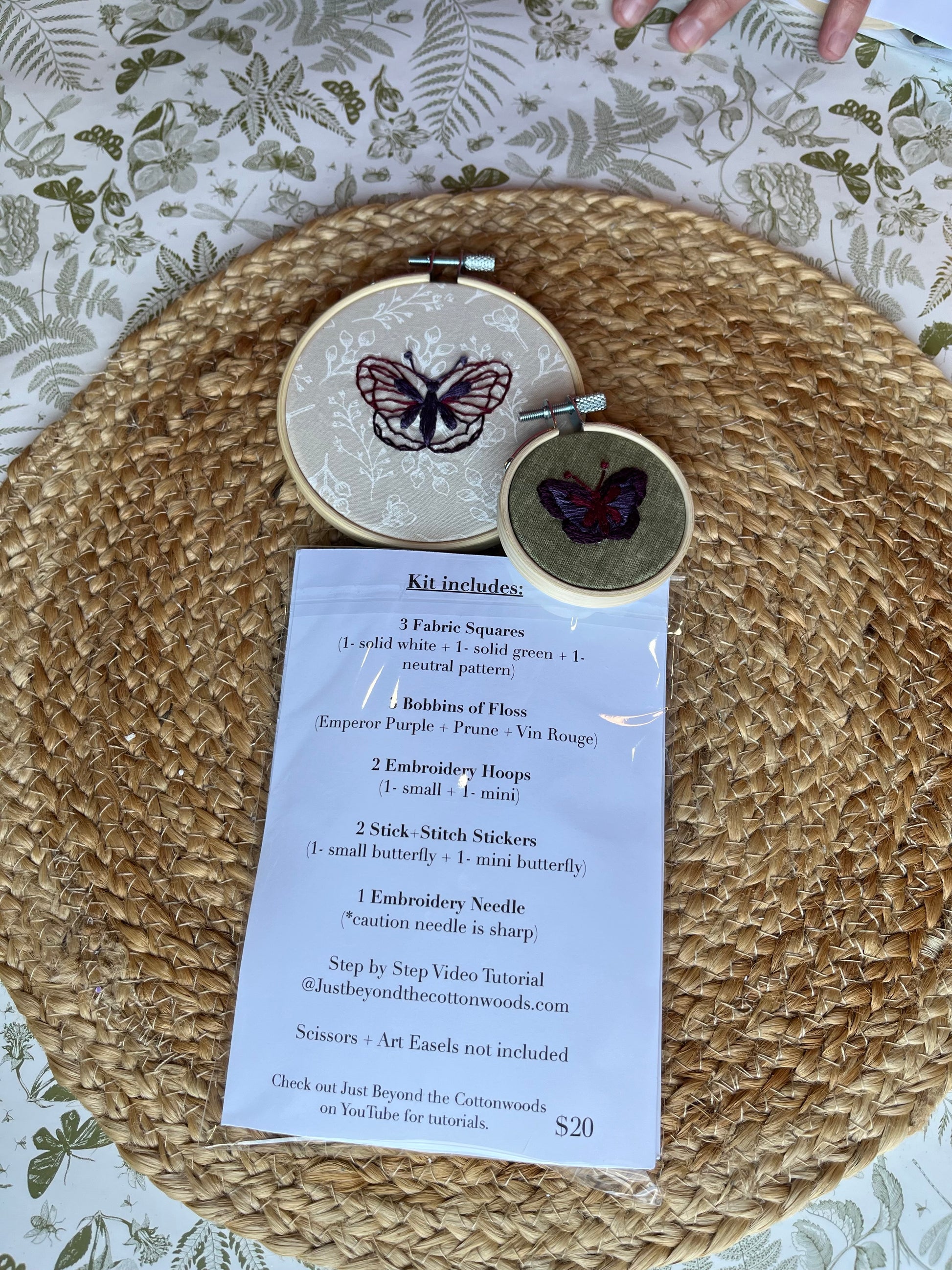 Embroidery hoop with butterfly design  and list of what is included on a textured surface