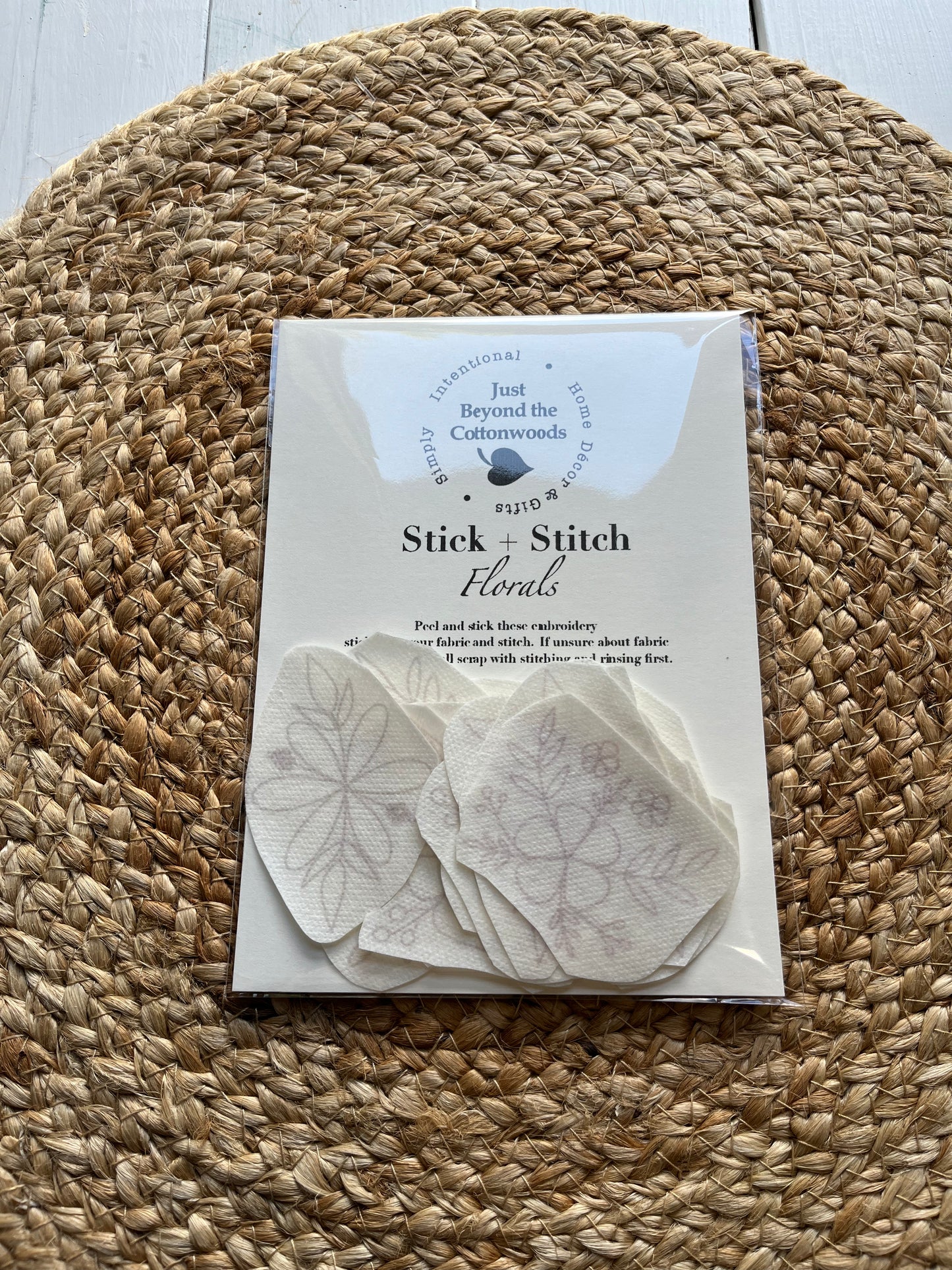 Packaging for 'Stick-n-Stitch' embroidery patterns, showing the product name Florals and a few examples of the embroidery designs on a woven mat background.