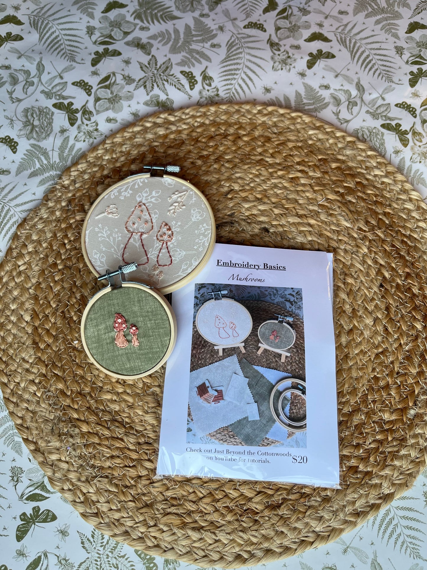 Embroidery hoops with embroidered designs on a woven mat with a patterned background