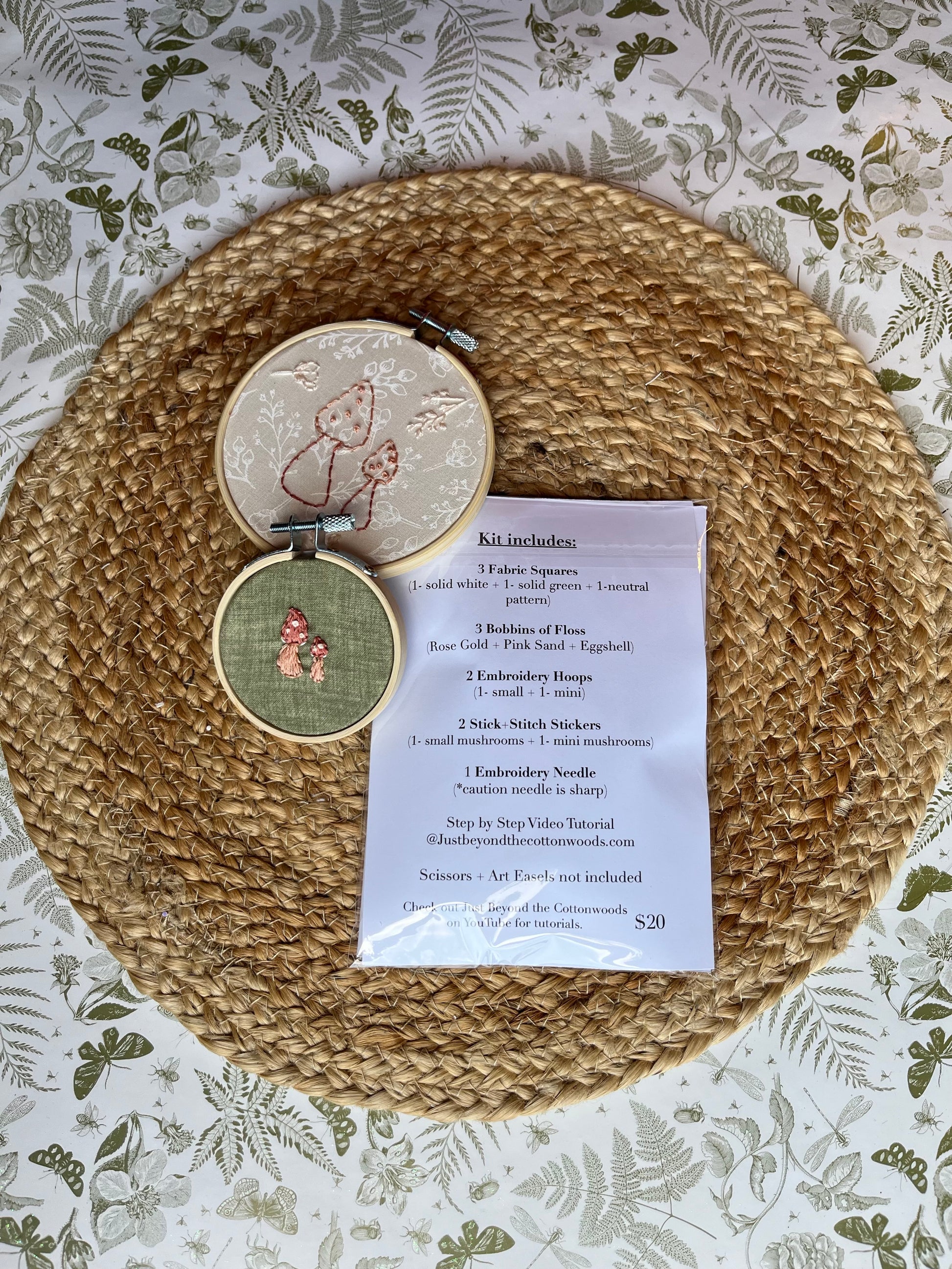 Embroidery kit with hoops and list of what is included in kit on a woven mat with floral pattern 