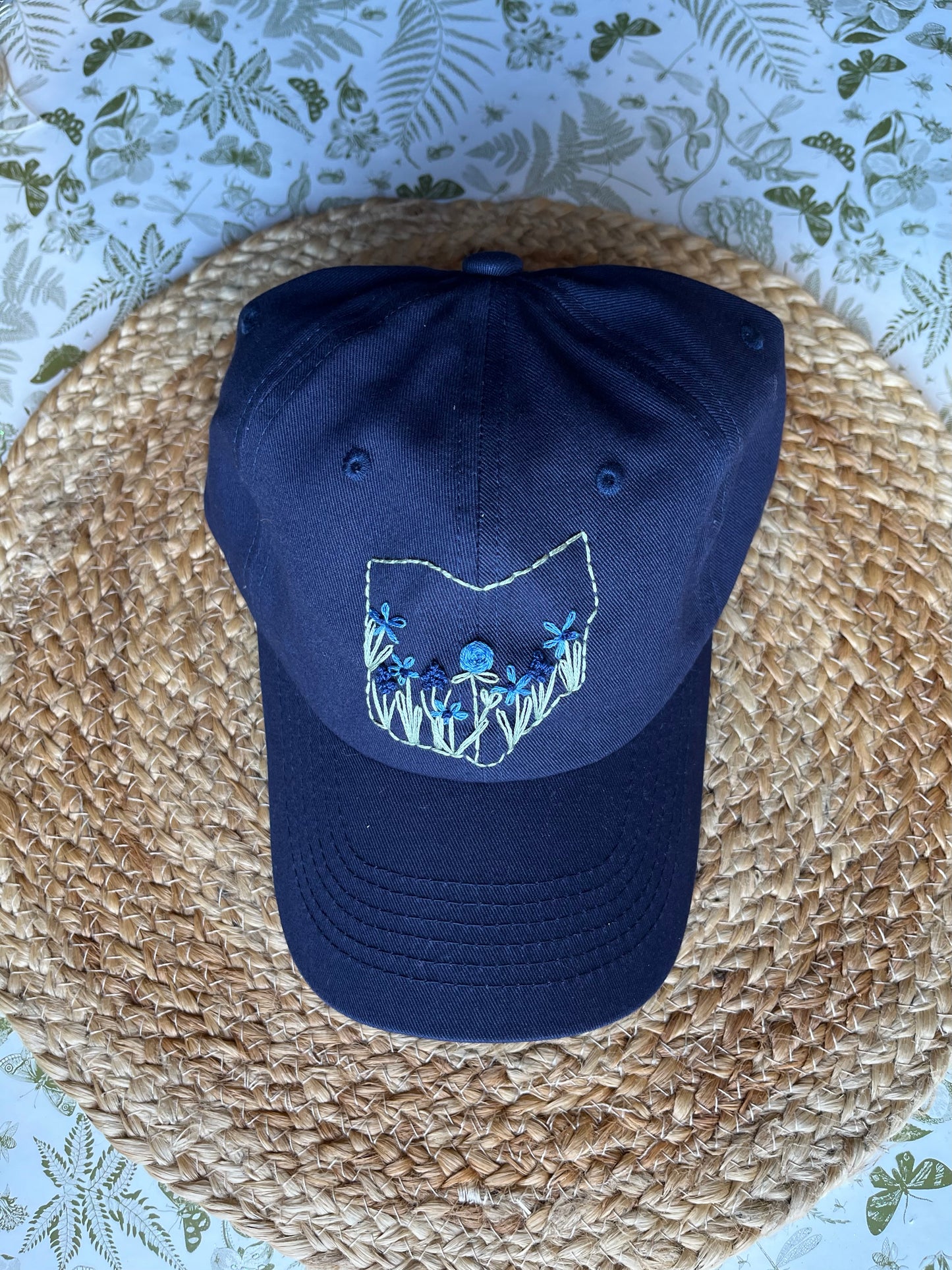 Navy blue cap with embroidered design on a woven surface