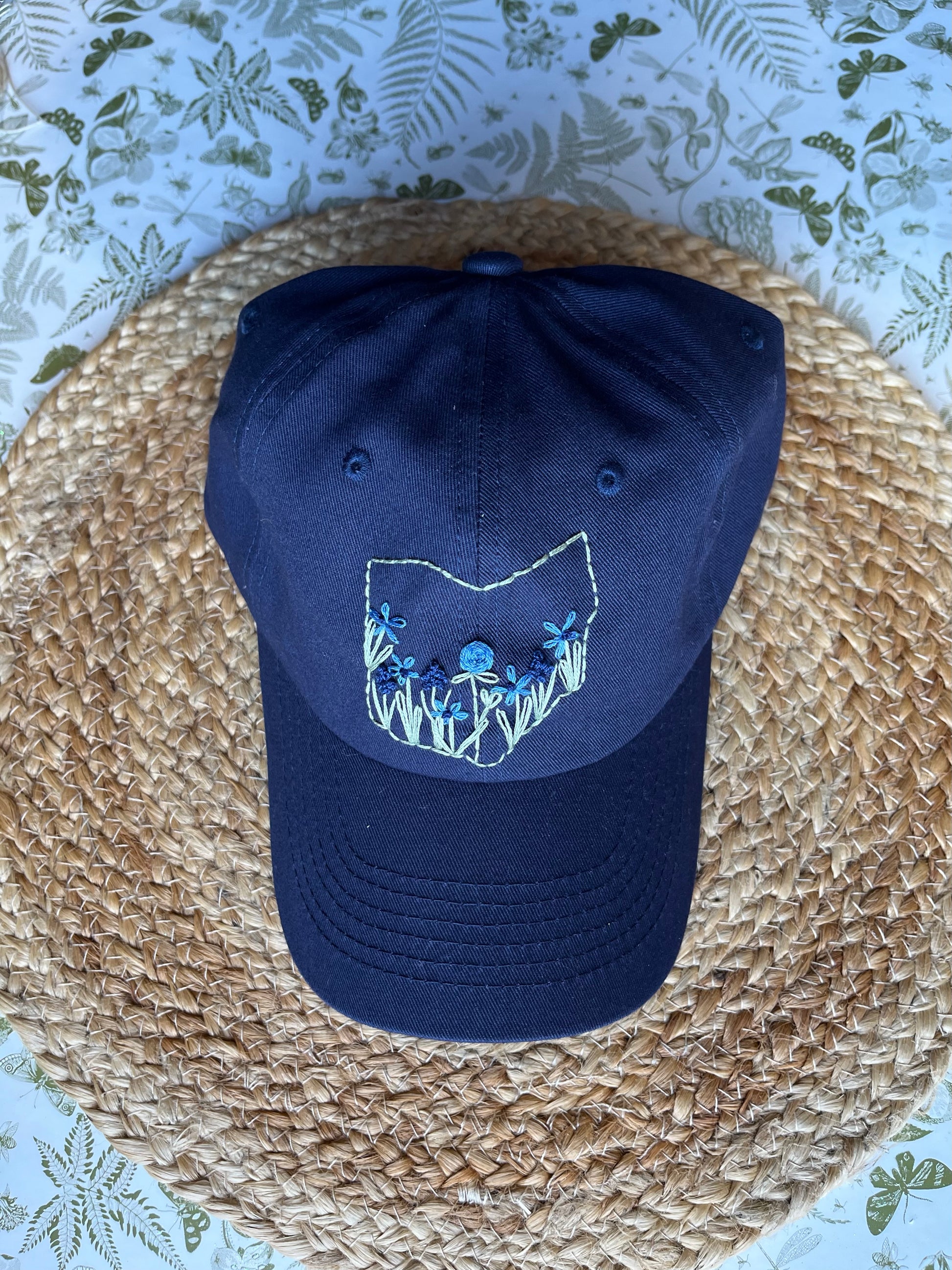 Navy blue cap with embroidered design on a woven surface