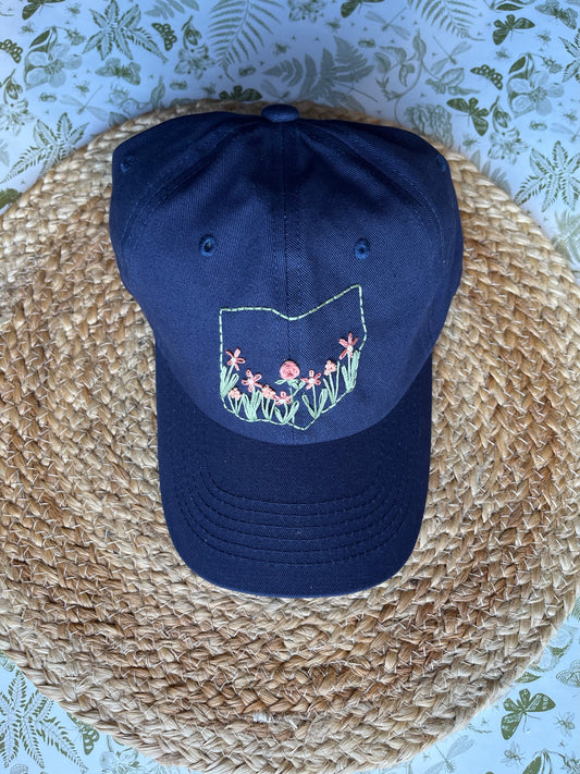 Navy blue cap with floral design on a woven surface