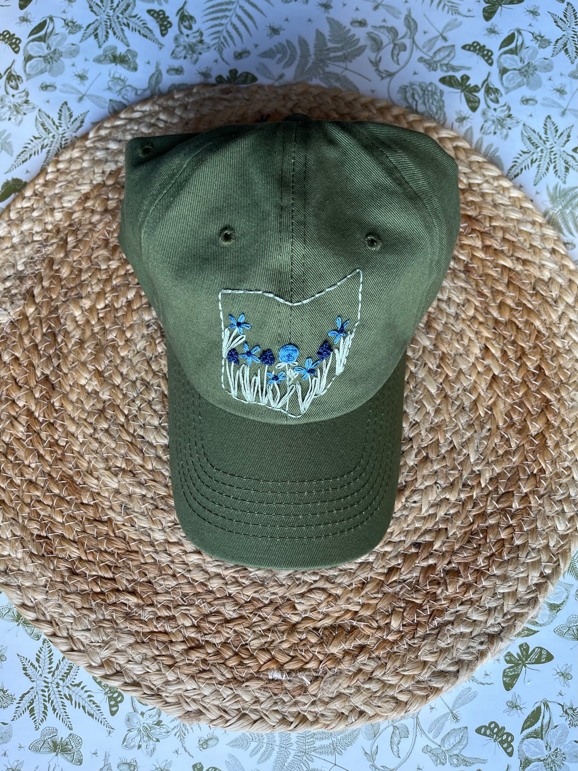 Green cap with floral embroidery on a woven surface