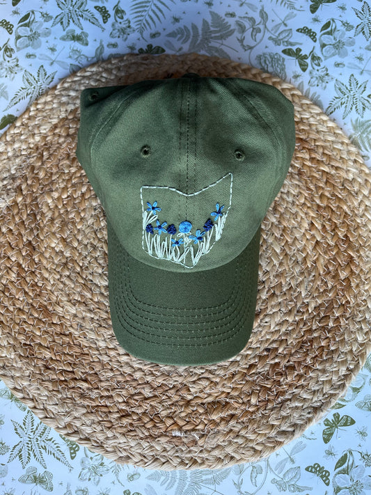Green cap with floral embroidery on a woven surface