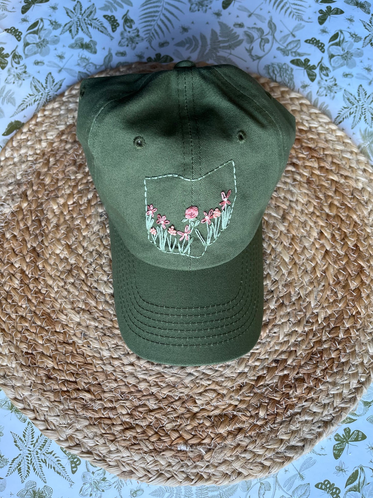 Green cap with floral design on a woven surface