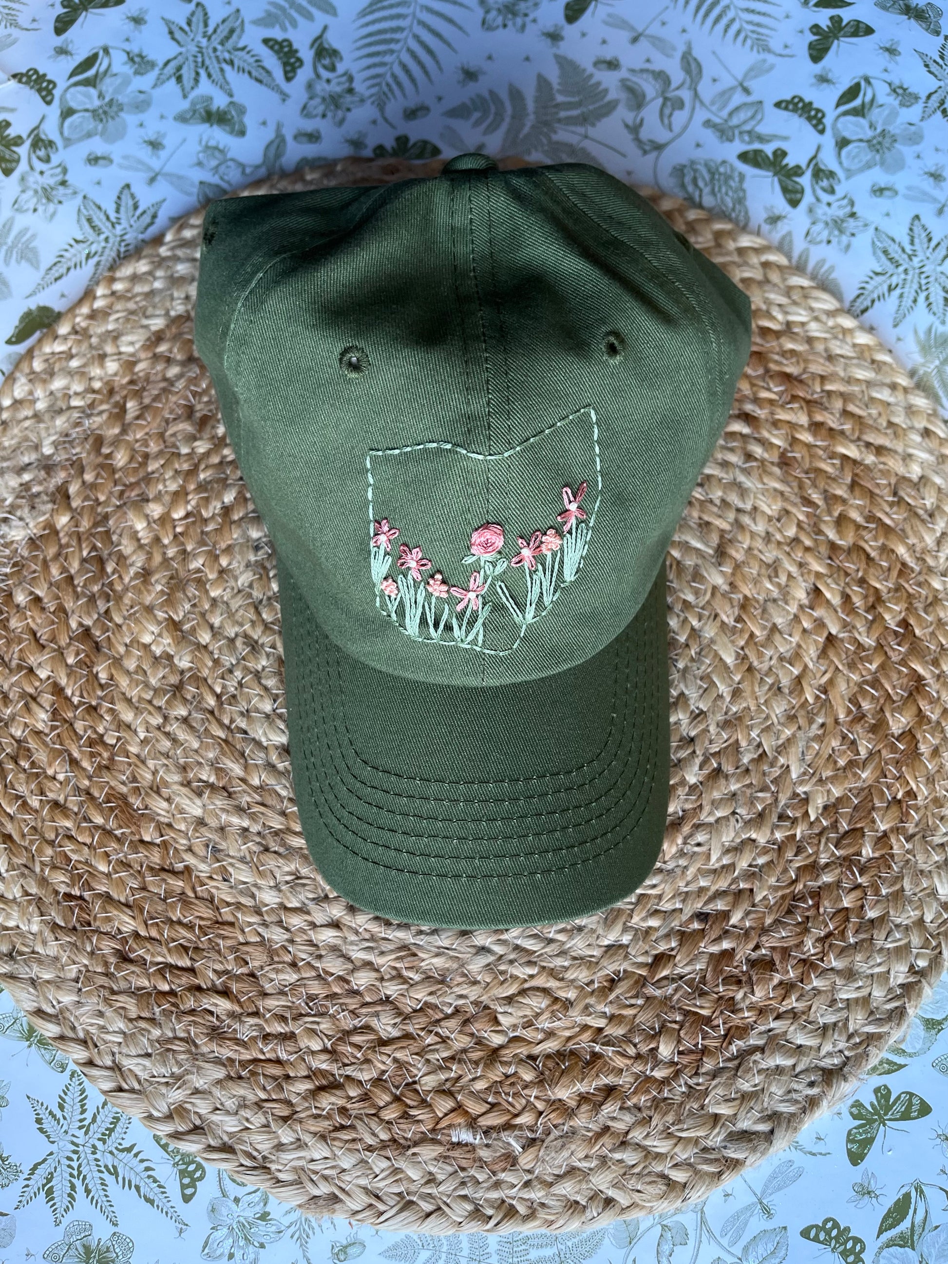 Green cap with floral design on a woven surface