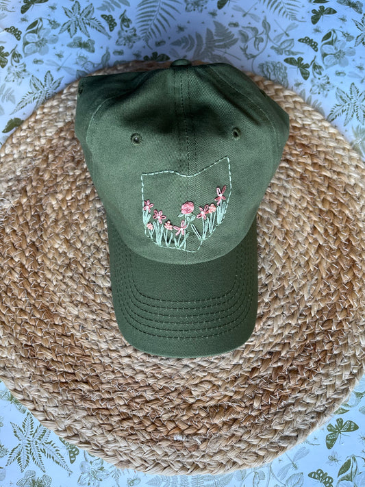 Green cap with floral design on a woven surface
