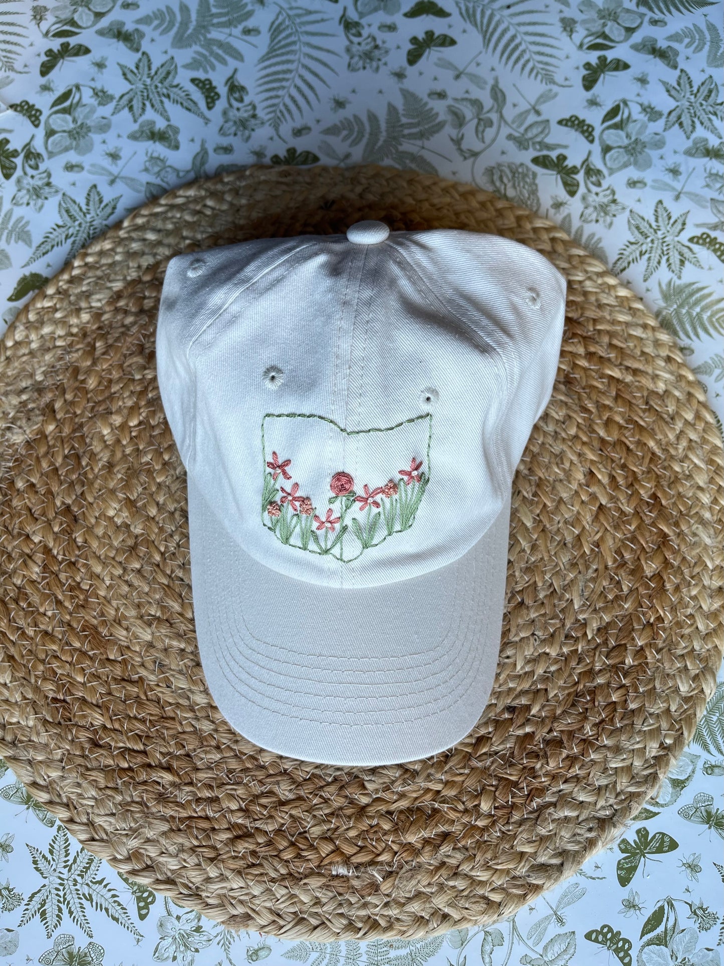White stone cap with floral design on a woven mat with floral patterned background