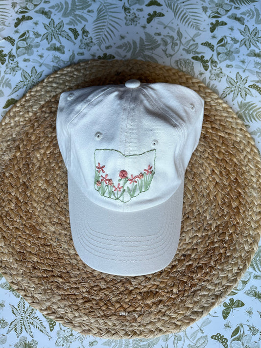 White stone cap with floral design on a woven mat with floral patterned background